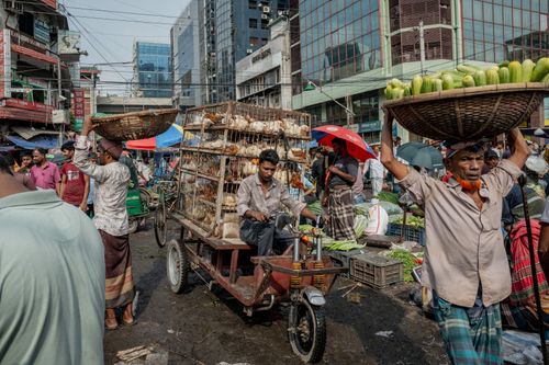 Free Dynamic market scene with people, goods, and a motorcycle cart in a bustling urban area. Stock Photo