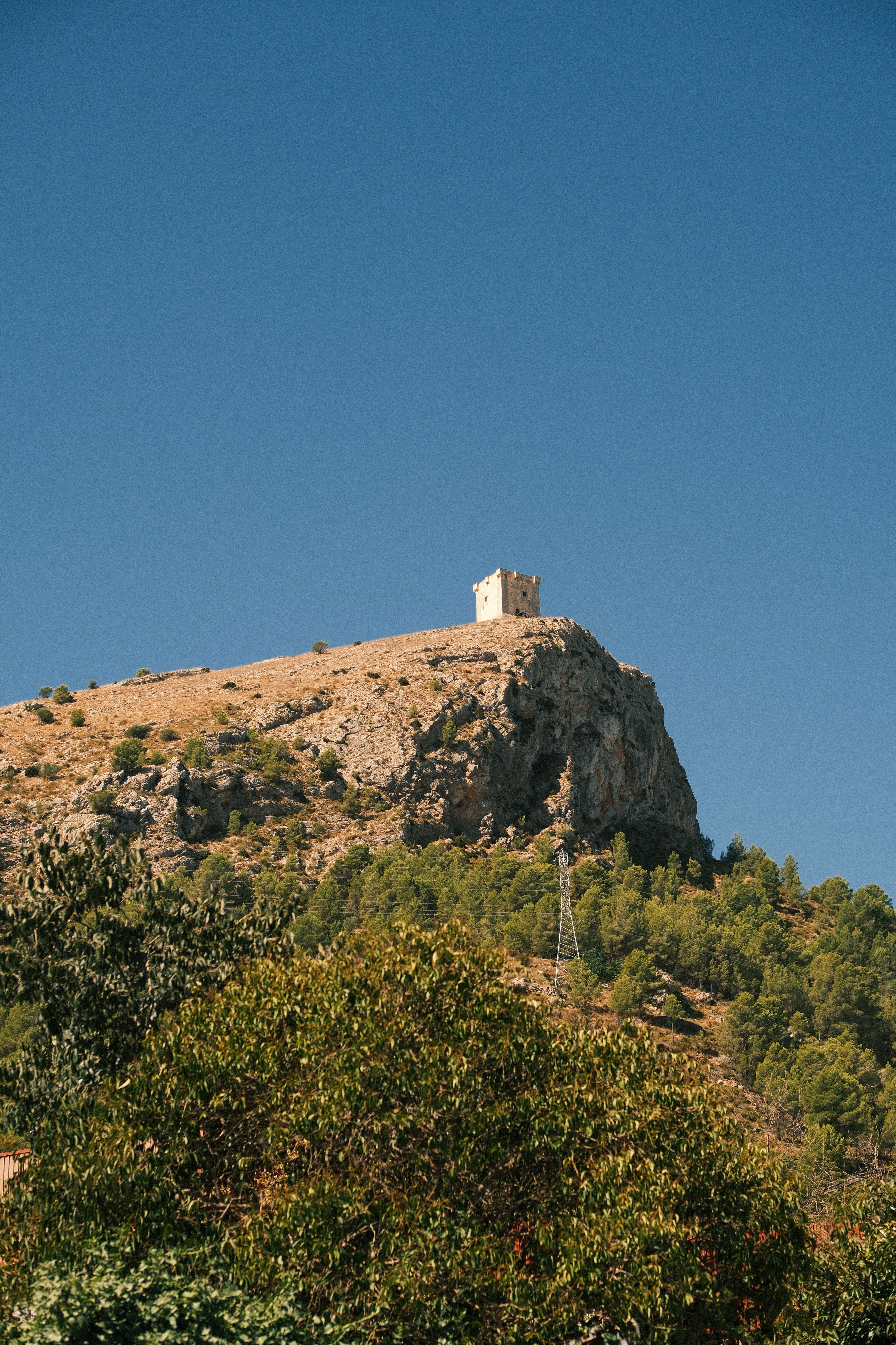 Stunning view of Hermit's Chapel atop a hill in Planes, Spain on a sunny day.