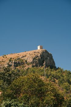 Stunning view of Hermit's Chapel atop a hill in Planes, Spain on a sunny day.