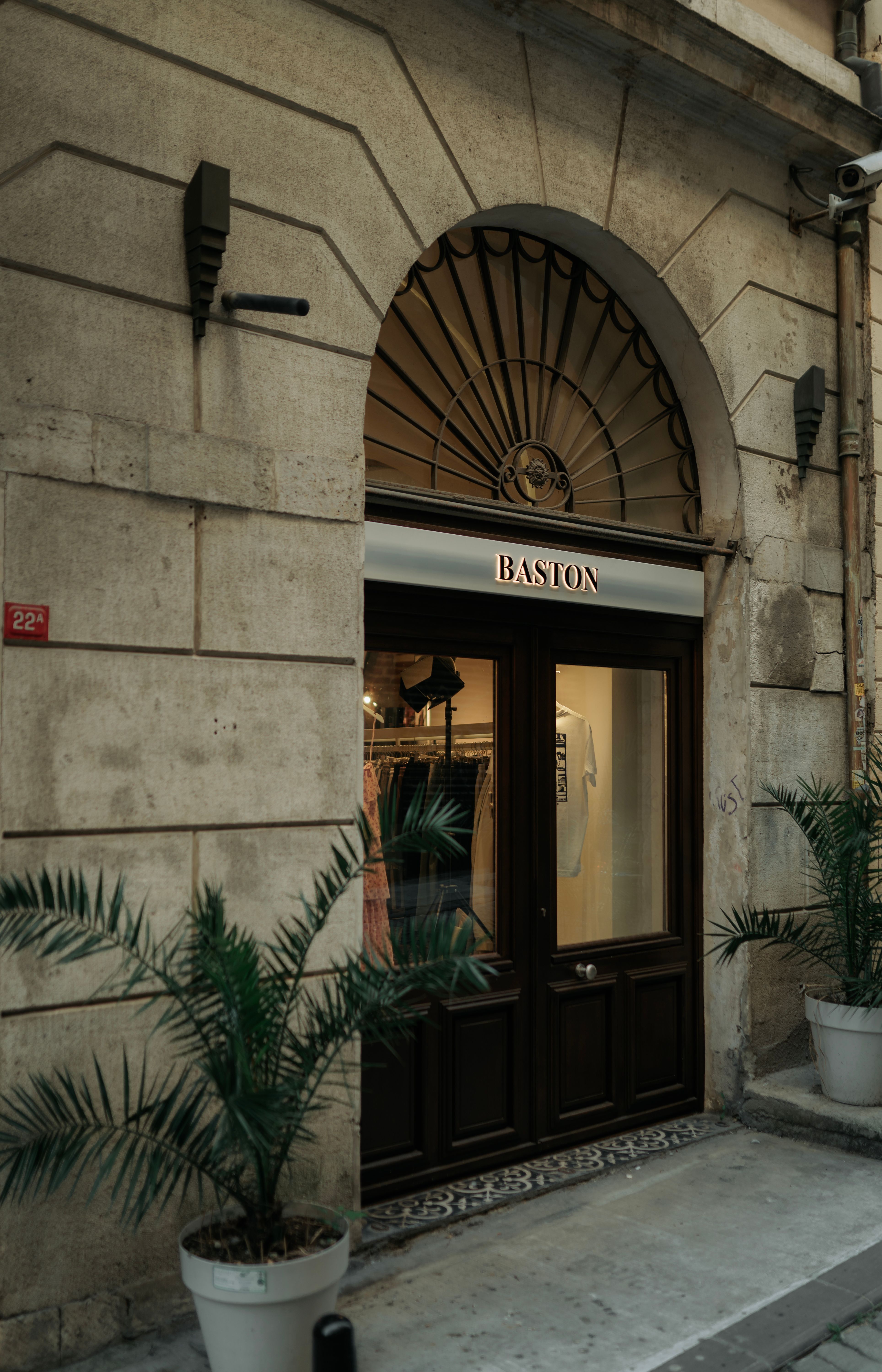 Elegant vintage-style storefront with arched entryway and potted plants on a quiet street.