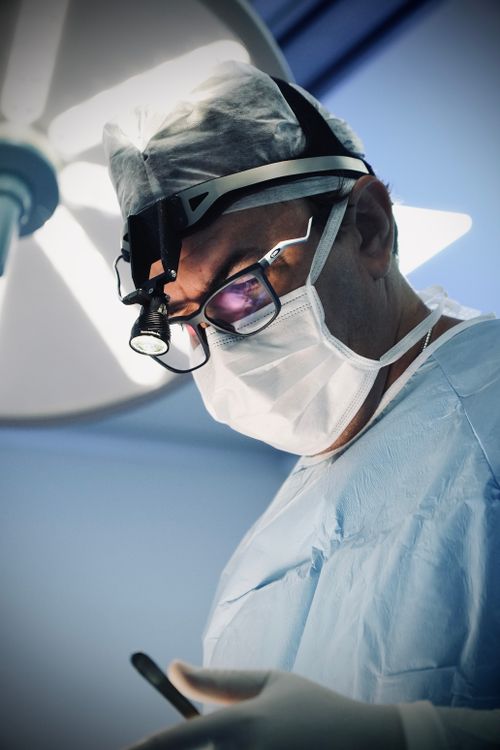 Free A skilled surgeon wearing a headlamp concentrates during surgery in a sterile operating room. Stock Photo