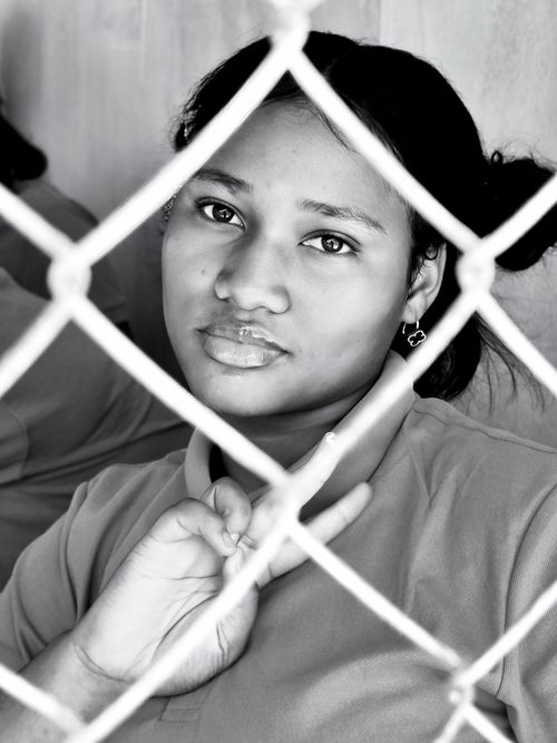 Free A contemplative portrait of a woman behind a fence in monochrome, capturing emotion and depth. Stock Photo