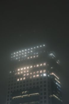 在雾气弥漫的夜晚，一座摩天大楼从迷雾中显现出来，窗户闪闪发光。 - 相关推荐
