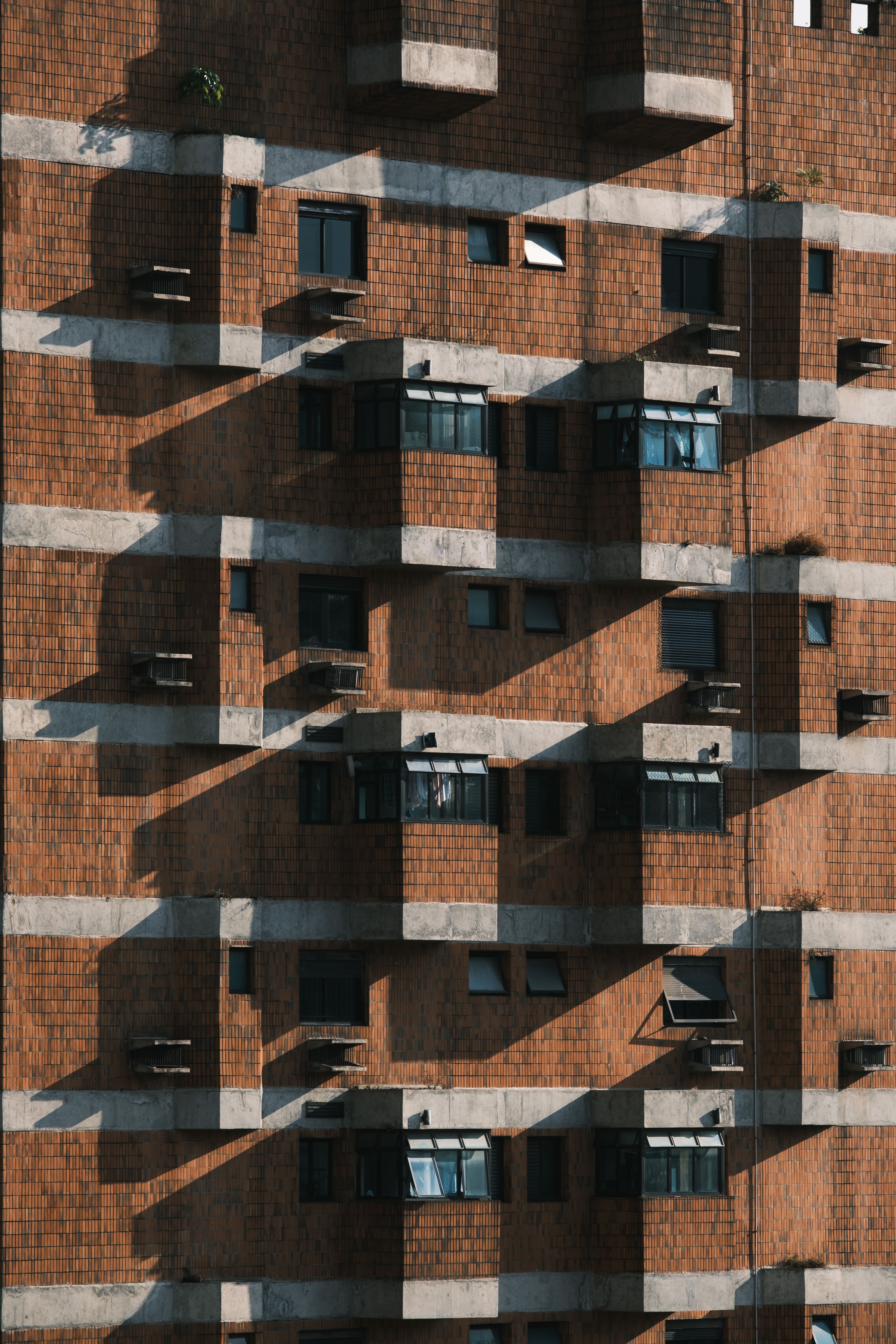 Geometric patterns of shadows on a brick apartment building facade.