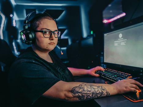 A focused gamer wearing headphones intently plays video games on a desktop computer.
