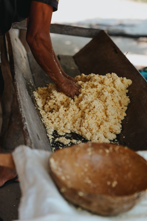 Free A person manually working with cassava dough in a rustic setting, showcasing traditional food preparation. Stock Photo