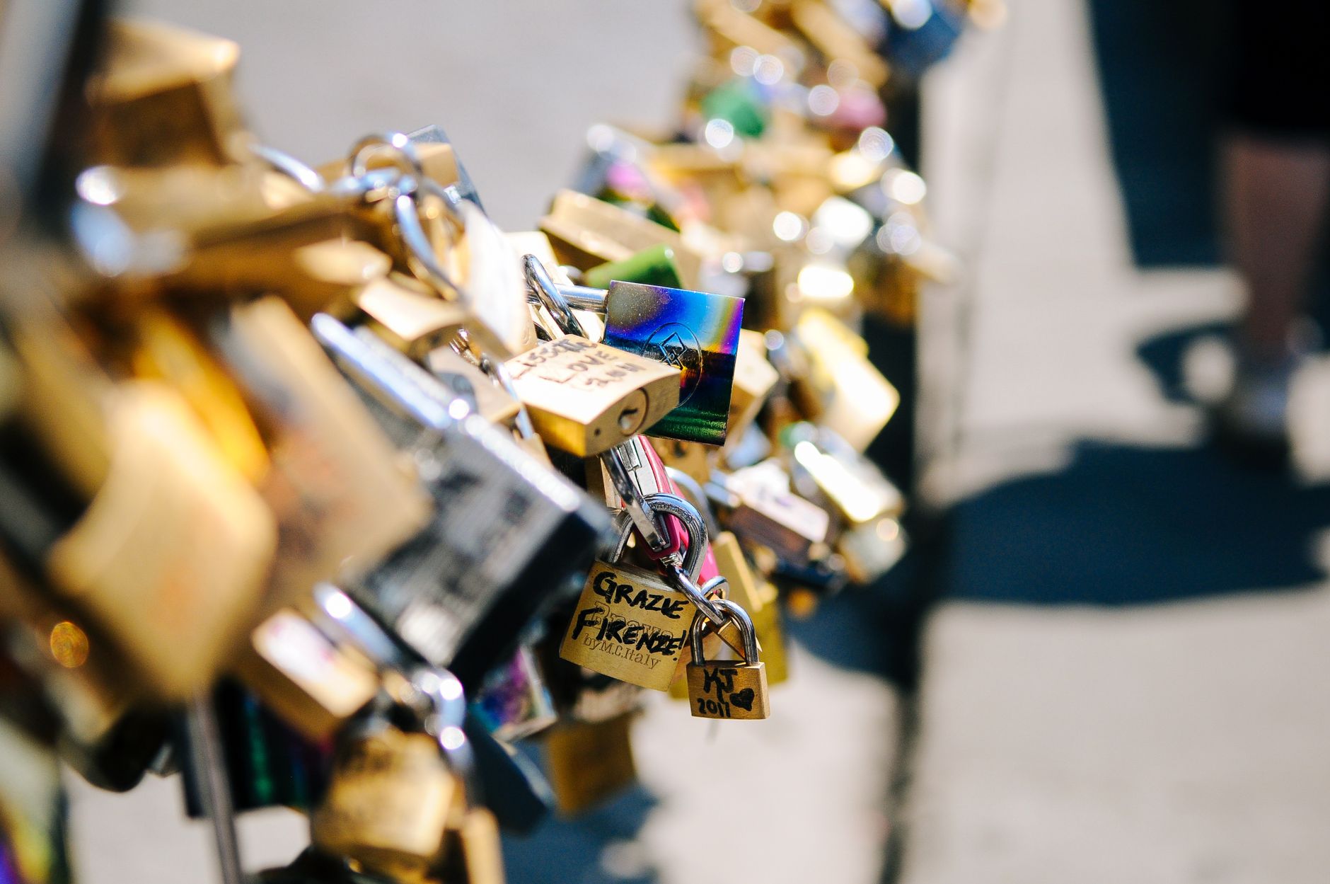 A collection of engraved love padlocks attached to a bridge symbolizing love and commitment.