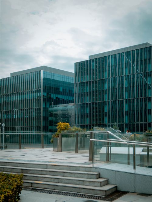 Free A view of modern office buildings with reflective glass facades under an overcast sky. Stock Photo