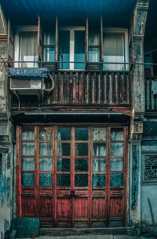 Free Rustic wooden facade with red doors, balcony, and air conditioner. Urban vintage architecture. Stock Photo