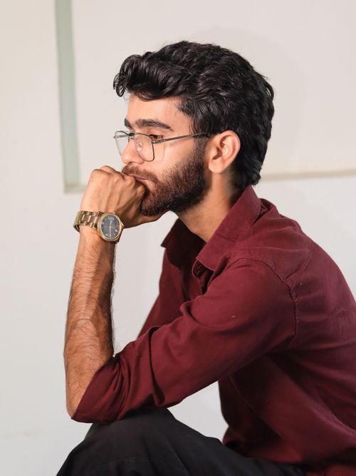 Free Side view of a thoughtful man in glasses wearing a red shirt, deep in contemplation. Stock Photo