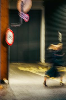 Abstract shot capturing blurred motion of a woman walking past signs at night in Warsaw.