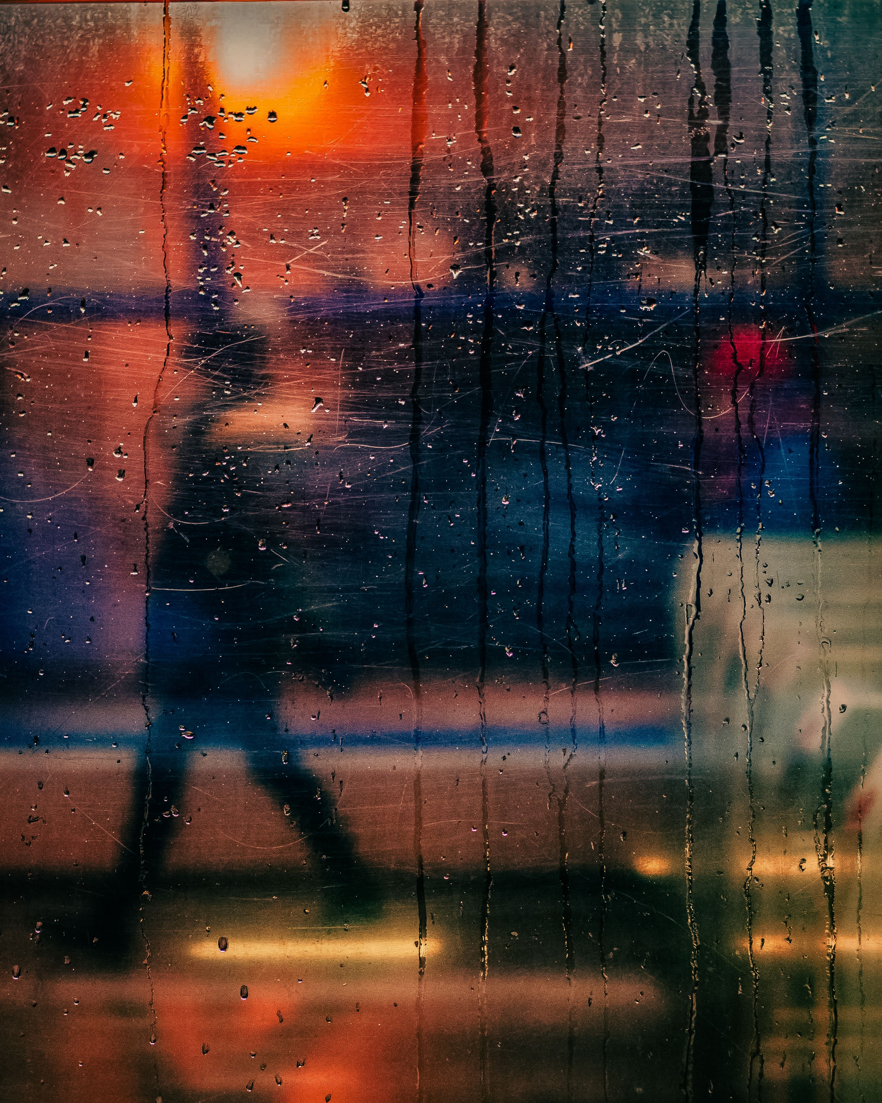 Blurry silhouette of a person walking behind a rain-streaked glass at night in Warsaw.