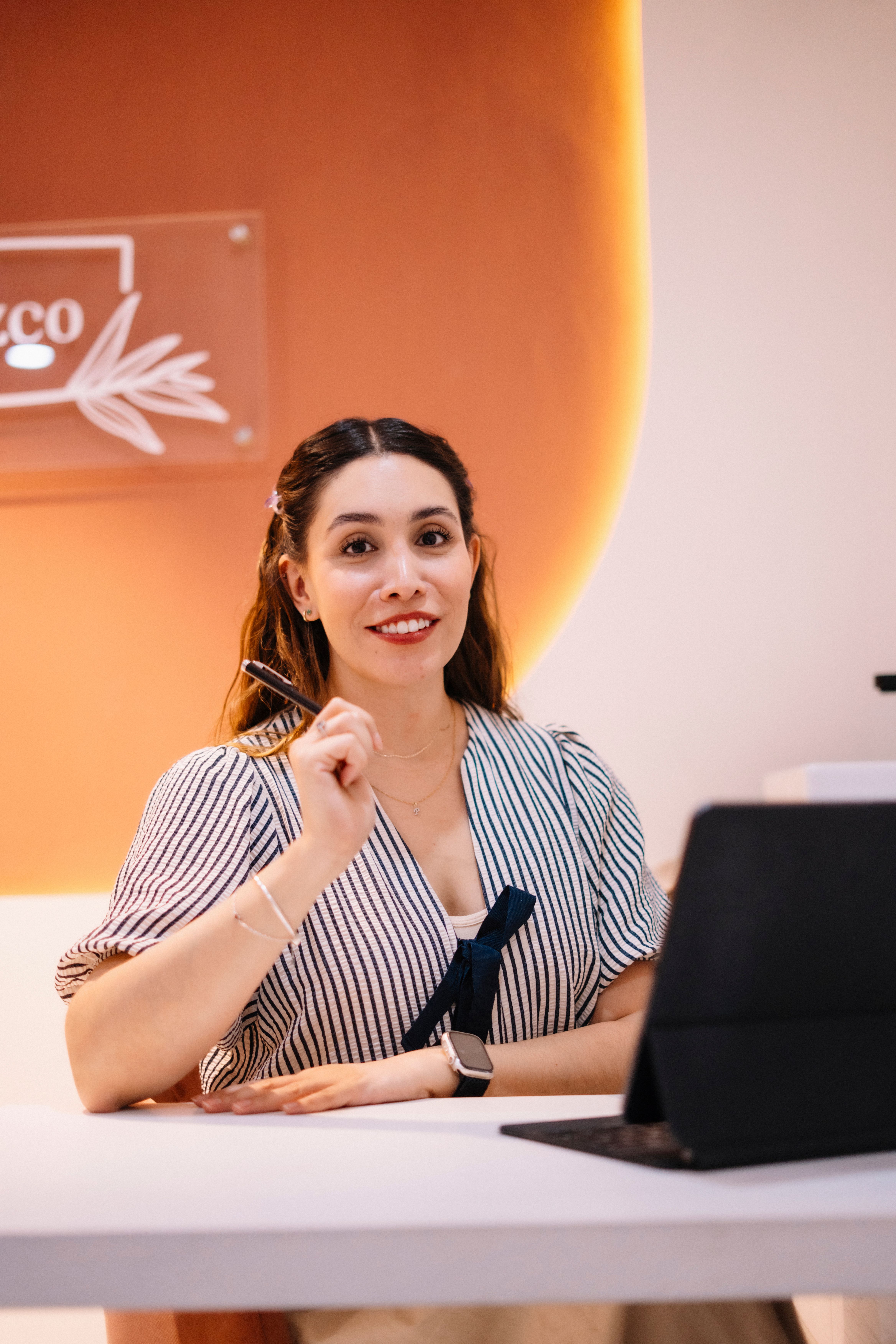 Businesswoman smiling confidently in stylish office with laptop, ready for a productive day.