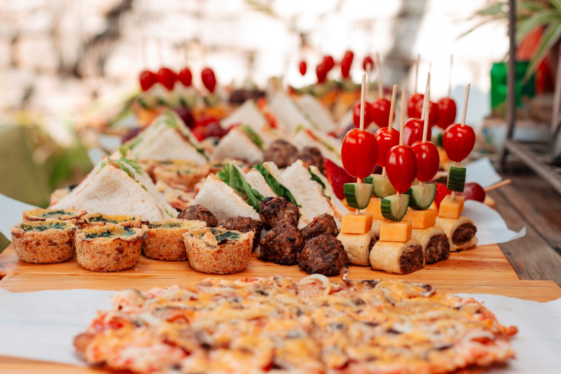A tasteful display of sandwiches, skewers, and pastries perfect for a garden party or picnic.