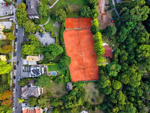 Free Aerial view of clay tennis courts surrounded by lush green trees in Austria. Stock Photo