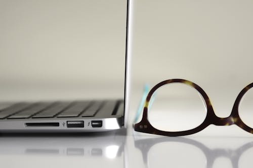 Free Black Framed Eyeglasses Beside Laptop Computer Stock Photo