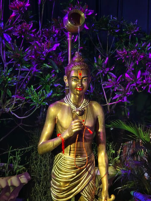 Free A golden statue with vibrant lighting surrounded by purple foliage, creating a mystical atmosphere. Stock Photo