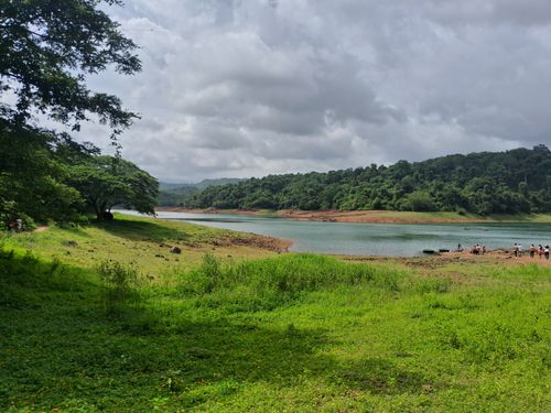 Free Beautiful river landscape with lush greenery and distant forest views under cloudy skies. Stock Photo