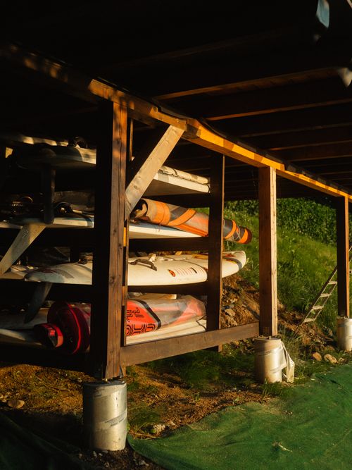 Free A collection of surfboards stored under a wooden structure, glowing in natural sunlight. Stock Photo