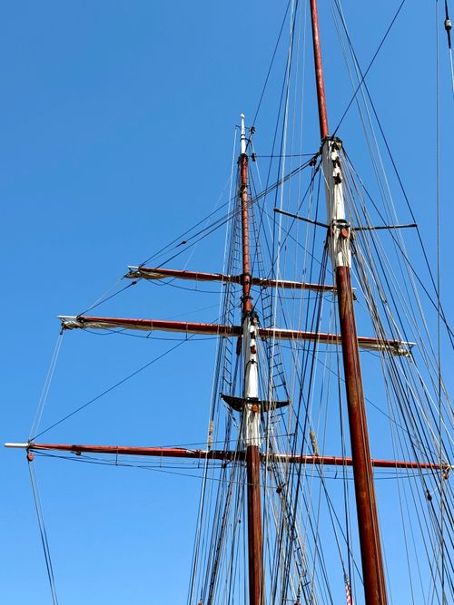 Free Close-up view of a tall ship's masts and rigging set against a clear blue sky, showcasing nautical craftsmanship. Stock Photo