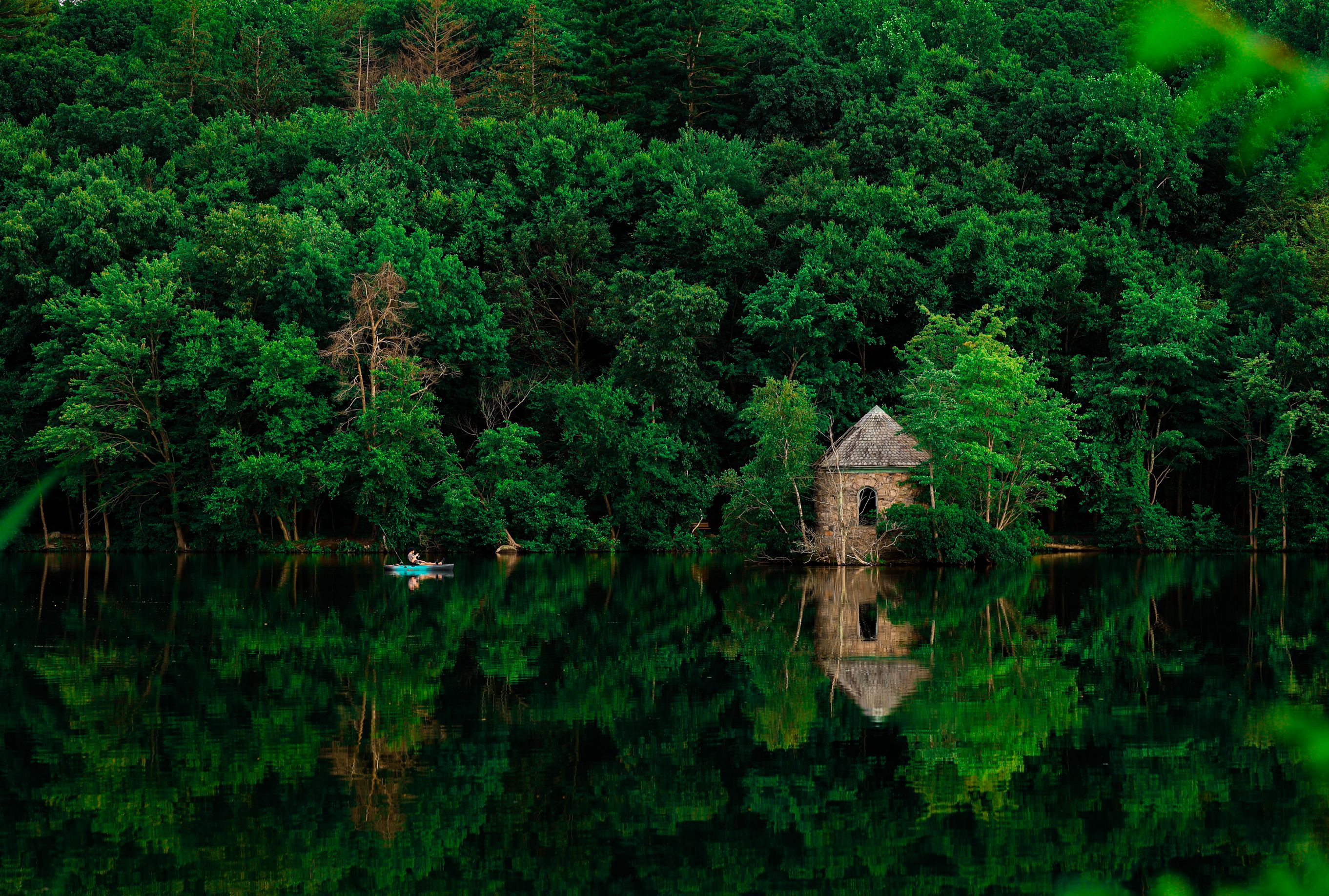 Tranquil lake scene with lush forest reflection and historic building.