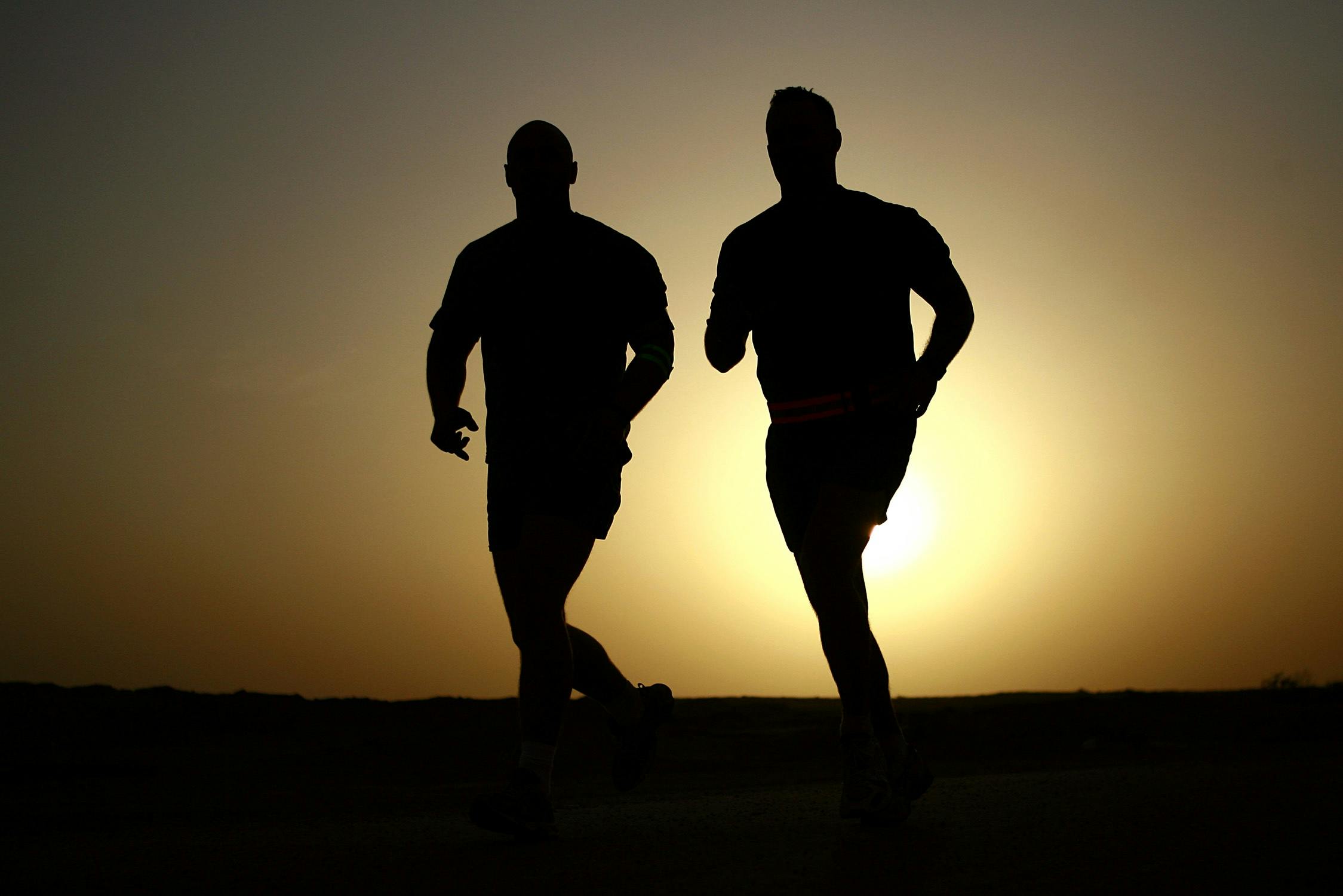 走っている二人の男のシルエット 無料の写真素材