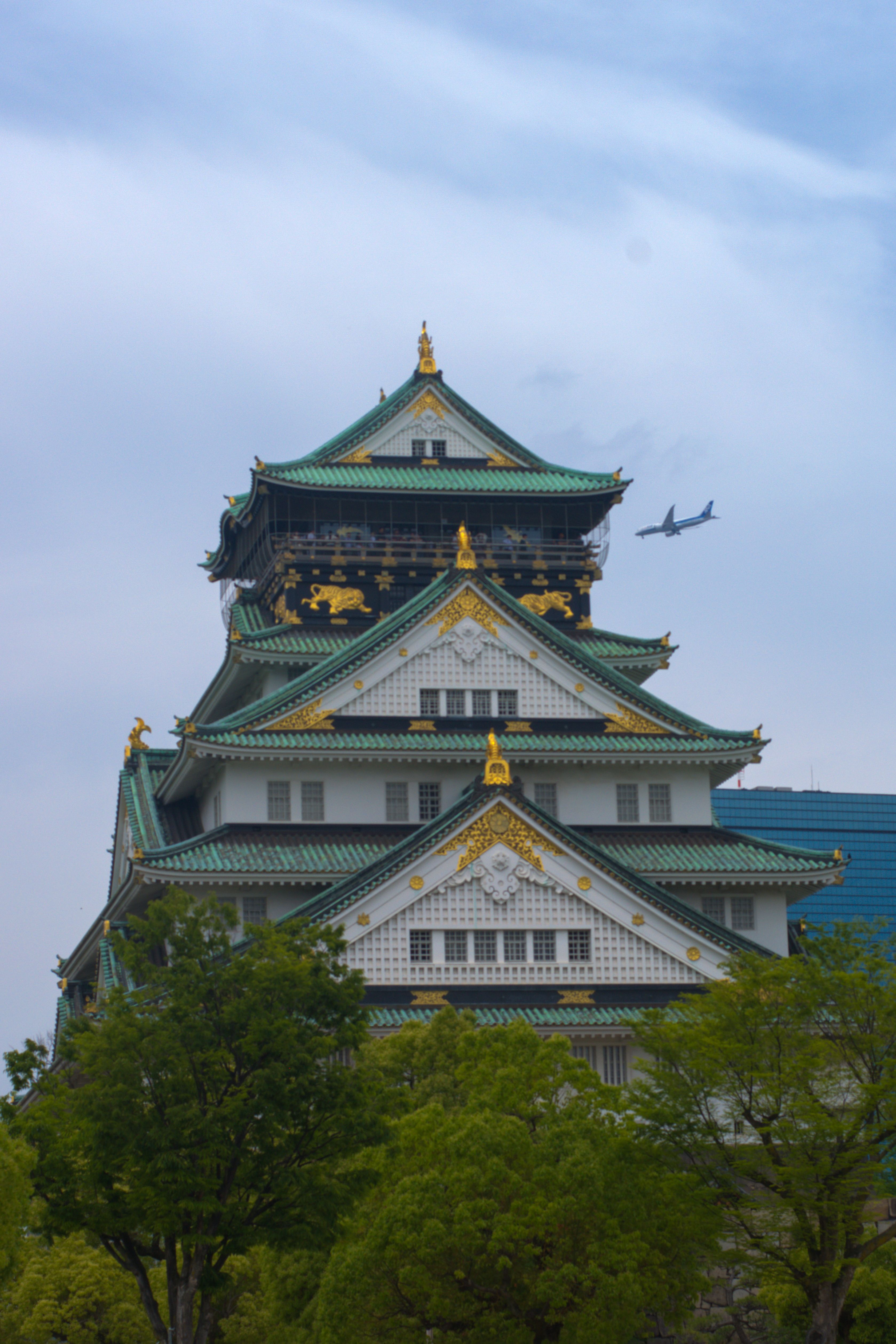 A stunning view of Osaka Castle with a plane flying above, capturing historical and modern elements.
