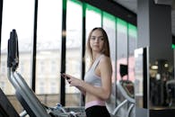一位年轻女子在健身房的大窗户旁，于跑步机上锻炼，践行着以健身为中心的生活方式