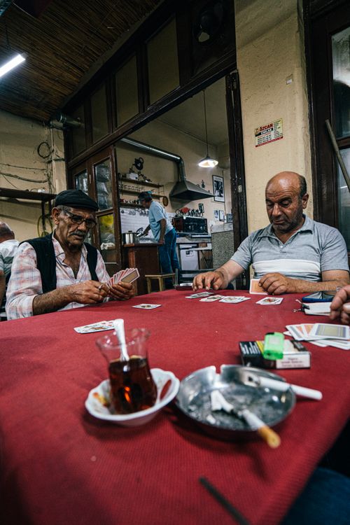 Free A group of men engaged in a friendly card game at a traditional café in Tire, İzmir, showcasing local culture and camaraderie. Stock Photo