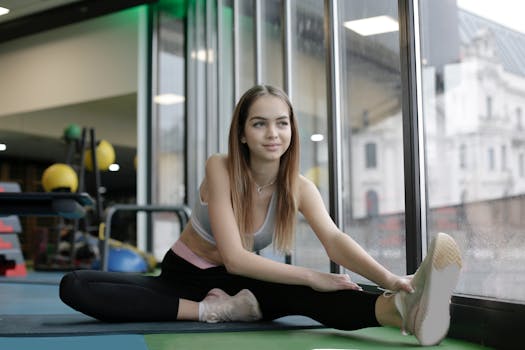 A young woman engaging in stretching exercises at an indoor gym. Ideal for fitness and wellness themes.