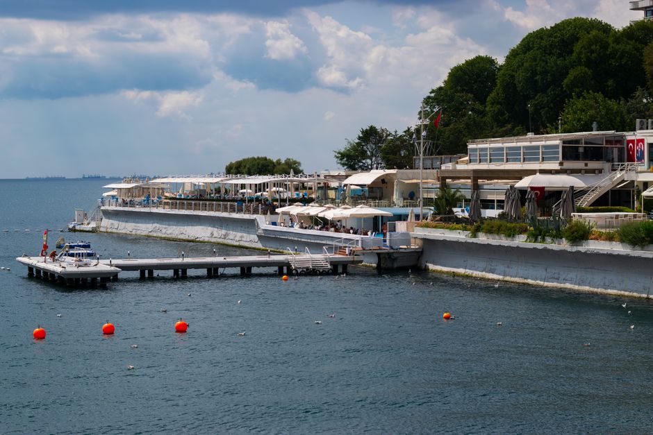 A scenic coastal resort with a pier extending into a deep blue sea under a cloudy sky.