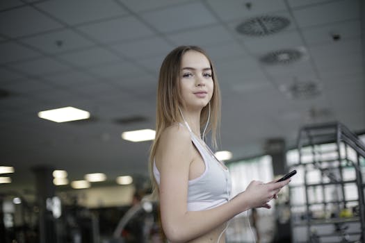 Young woman using smartphone in gym, enjoying workout with headphones.