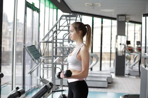 Free Fit young woman working out with dumbbells in a well-equipped modern gym. Stock Photo