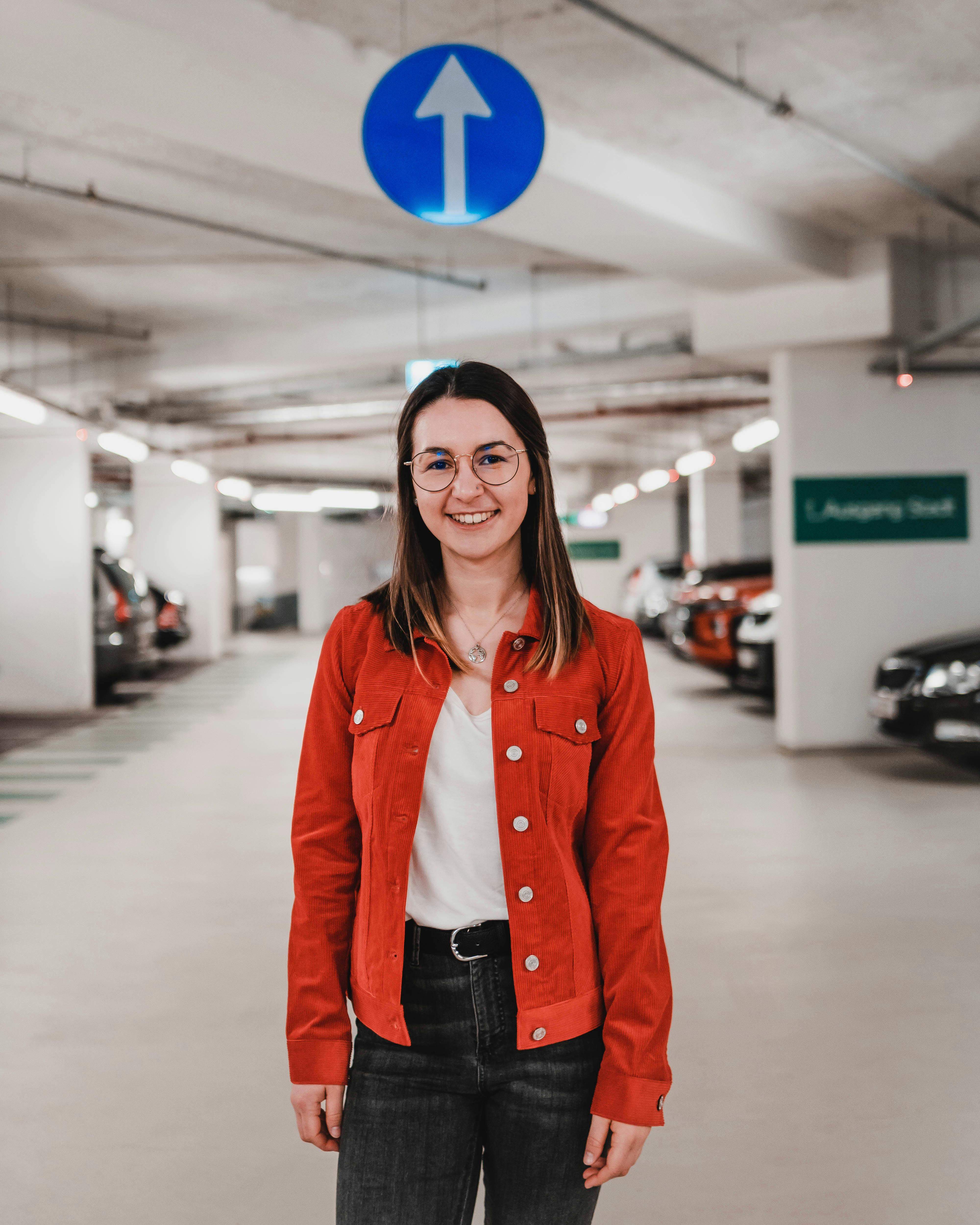 Casual fashion portrait of a smiling woman in an urban parking garage in Linz, Austria.