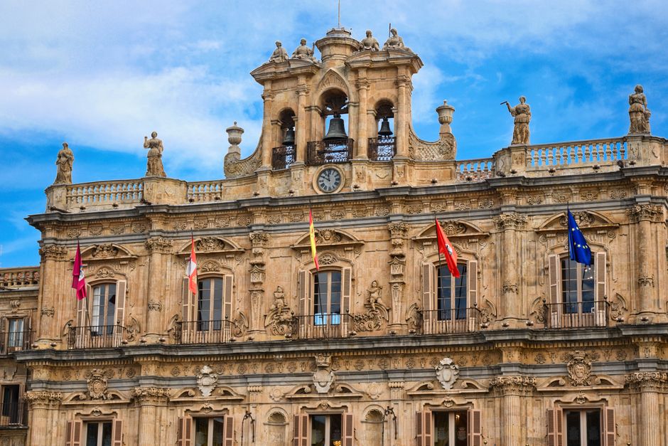 Una vista detallada de la imponente fachada de la histórica Plaza Mayor de Salamanca, España, bajo un cielo azul brillante.