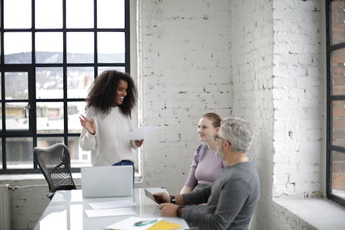 Free Cheerful colleagues discussing project together in light modern office Stock Photo