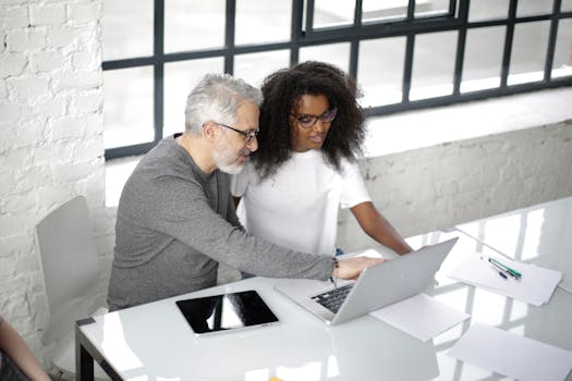 A diverse team collaborating on a project using a laptop in a bright office space.