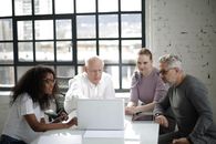 Man In White Long Sleeved Shirt Presenting on a Laptop
