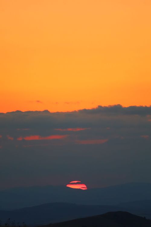 Free A stunning sunset over mountain silhouettes with vivid orange and pink hues. Stock Photo