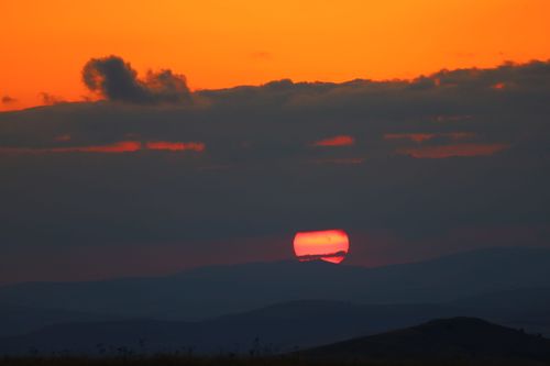 Free Vibrant sunset behind mountain silhouette with orange and red sky. Stock Photo