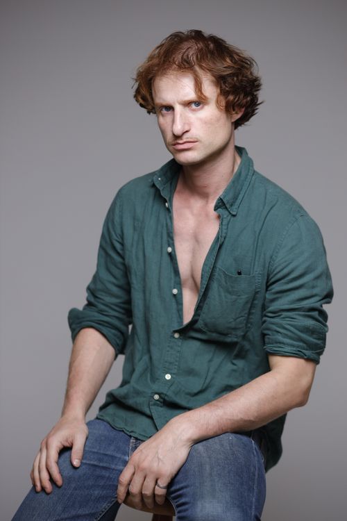Free An introspective young man in a green shirt poses against a neutral background. Stock Photo