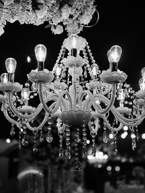 Free Black and white photo of a glowing crystal chandelier at night, exuding elegance. Stock Photo