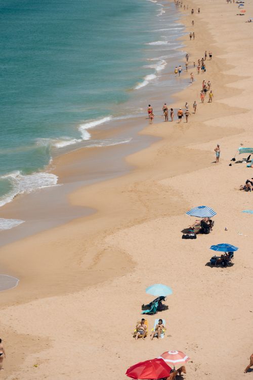 Free Aerial view of a crowded sandy beach with colorful umbrellas on a sunny day. Stock Photo