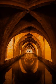 Mesmerizing reflection of gothic arches in the historic Alcazar baths in Seville, Spain.