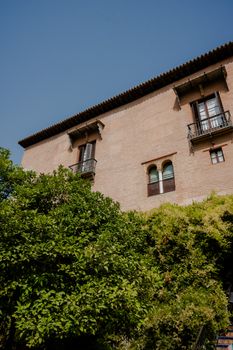 Historical building façade with lush greenery and clear blue sky, offering a serene architectural scene.