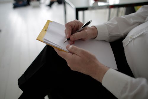 Free Unrecognizable businessman taking notes in documents in modern office Stock Photo