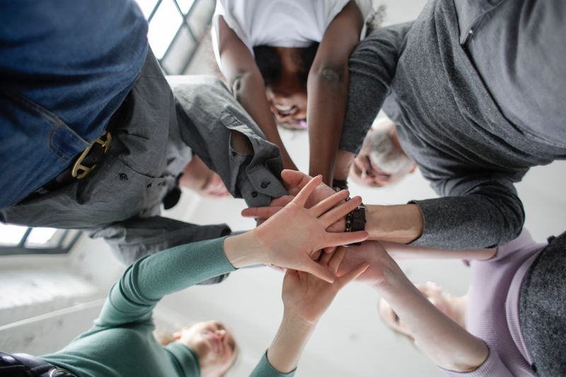 Diverse group joining hands together, symbolizing support