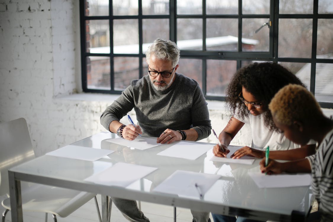 People Sitting Near Table Writing