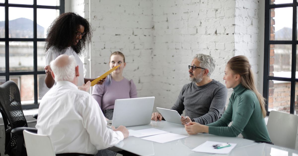 Un equipo de profesionales diversos discutiendo un proyecto en un entorno de oficina moderna con portátiles y documentos.
