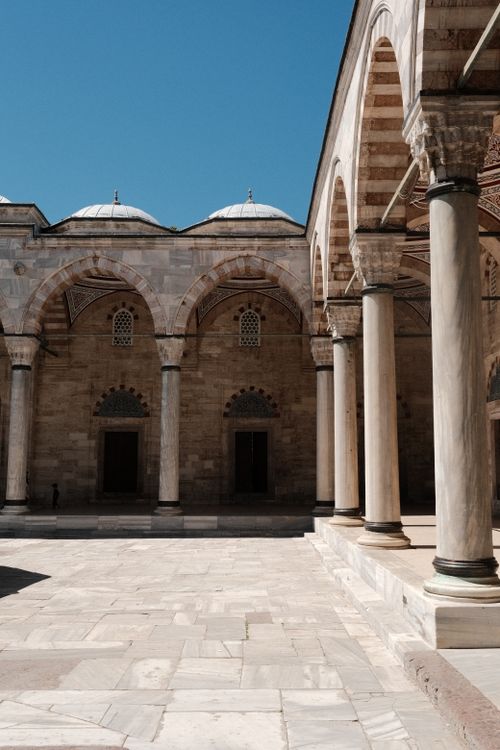 Free Elegant arches with detailed columns and domes in a serene courtyard under a clear blue sky. Stock Photo